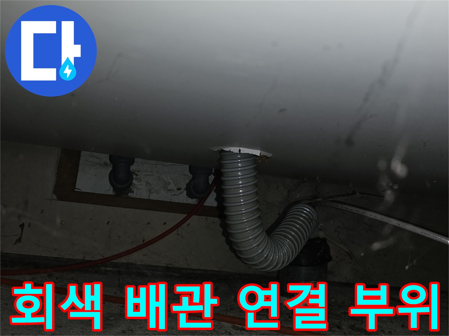 주방 싱크대 하단-노출된 회색 주름관과 벽면 배관 연결 상태