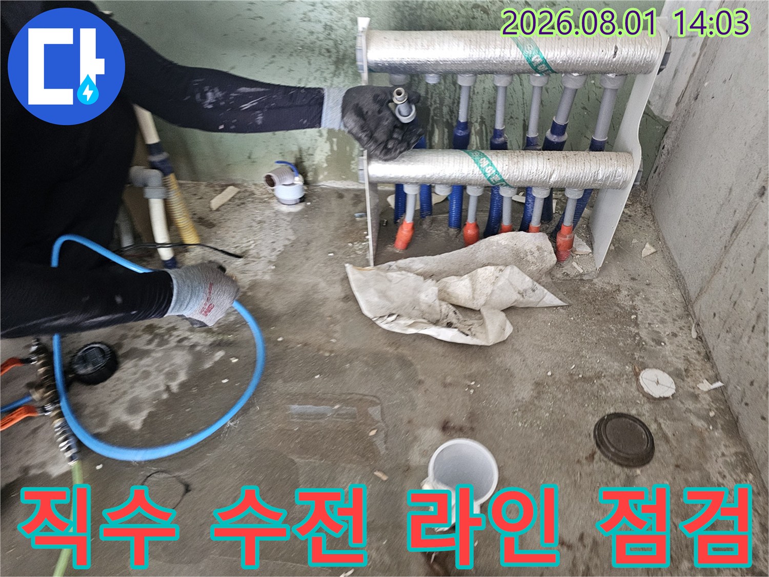 세탁실 내부 노출된 직수 배관과 분배기 연결부를 정밀하게 검사하는 장면