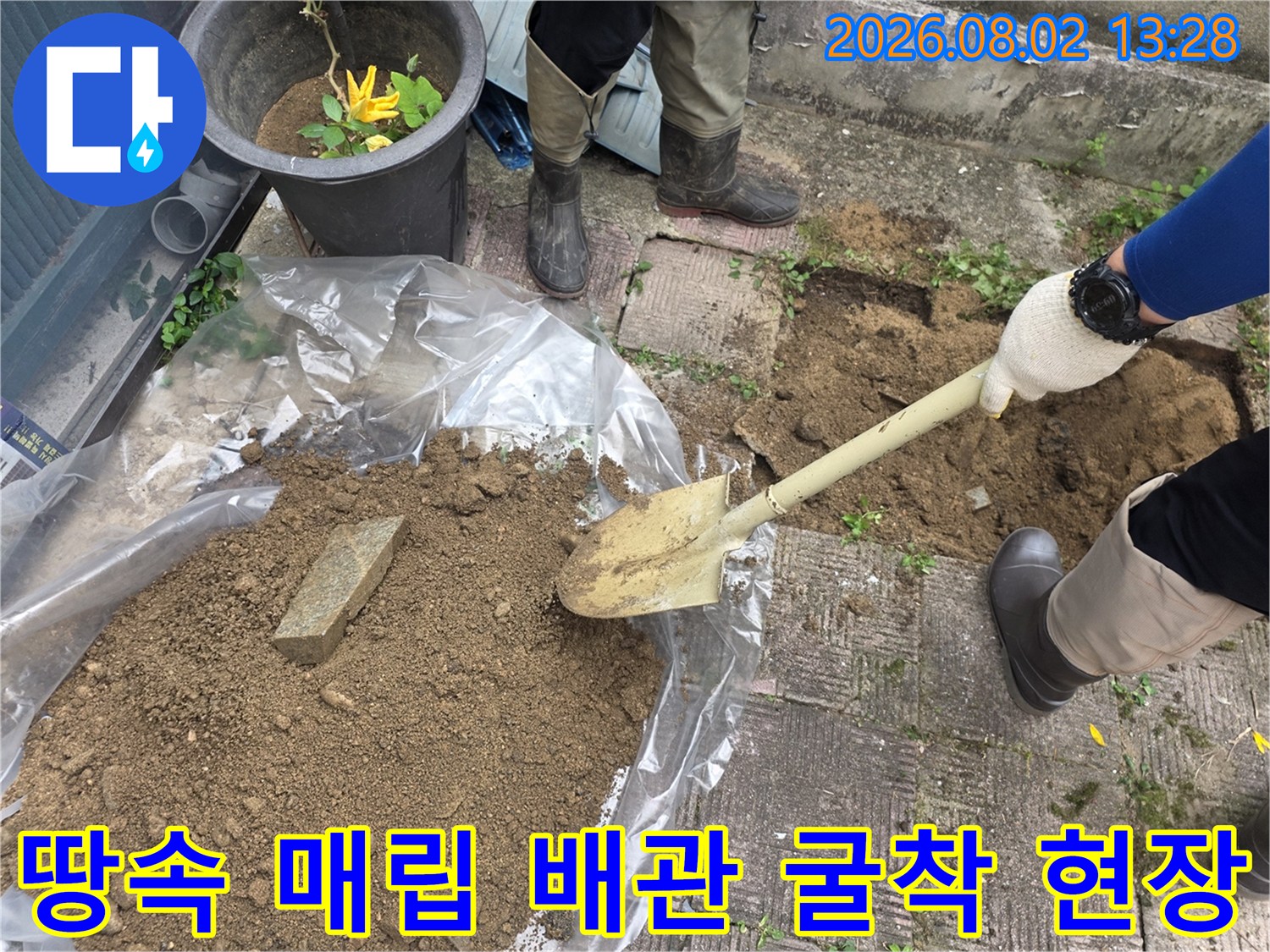 작업자가 삽을 들고 노출된 배관 주변 흙을 치우는 장면