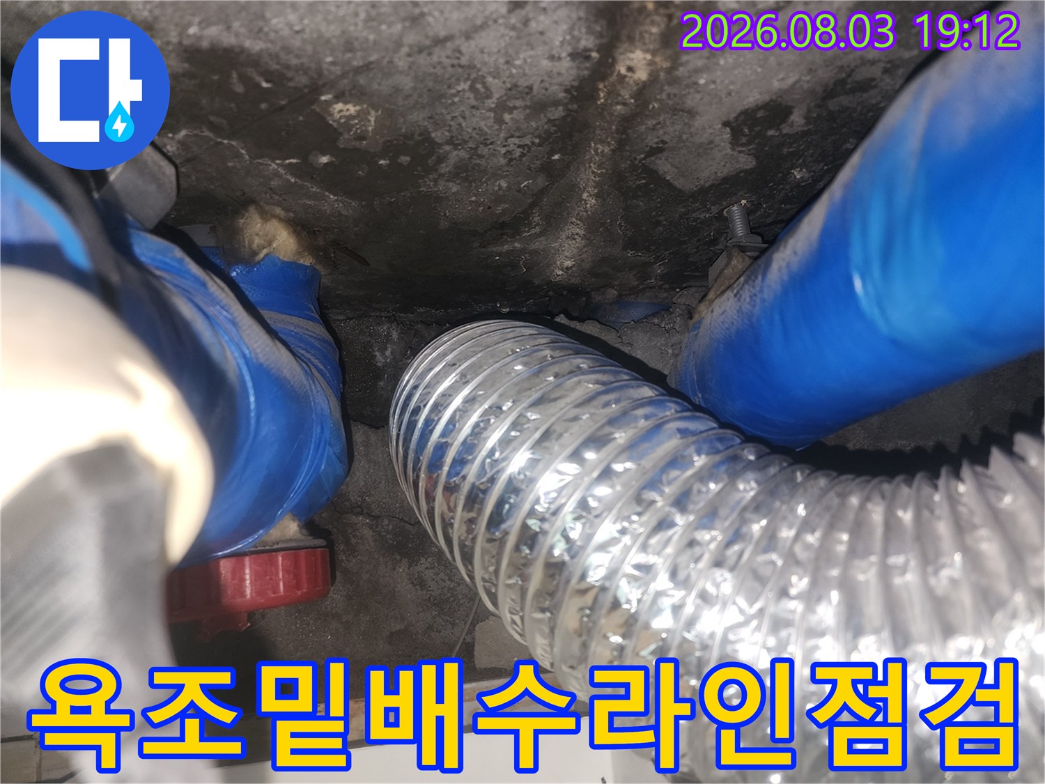 욕조 하부의 배수 트랩과 연결된 은색 유연 호스 점검 장면