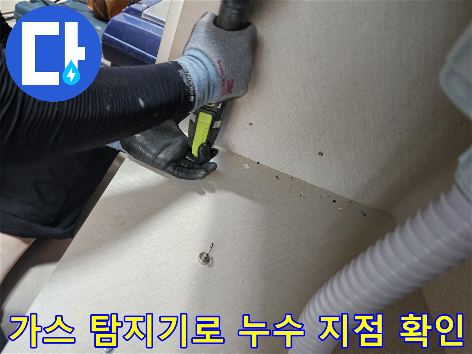현관 하부장 아래 공간에서-가스 탐지기를 이용해-배관의 누수 지점을 찾는 모습
