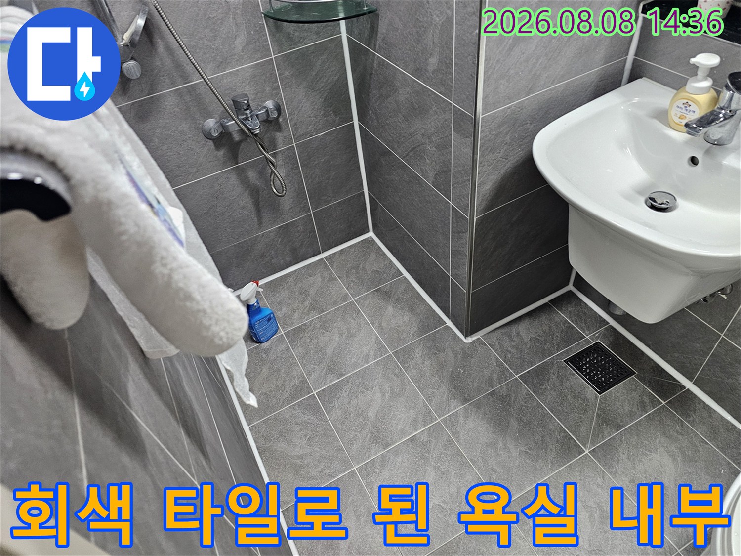 깨끗하게 시공된 회색 욕실 타일과 세면대 모습입니다.