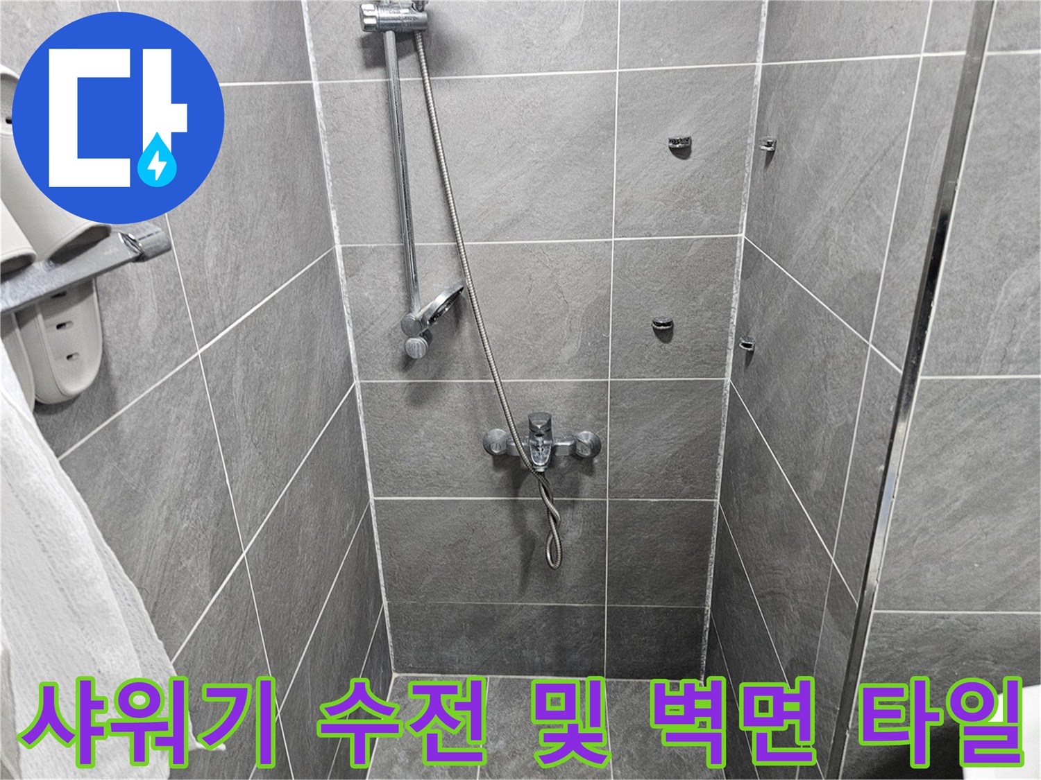 어두운 회색 타일 벽면에 부착된 샤워기 수전과 호스 연결부