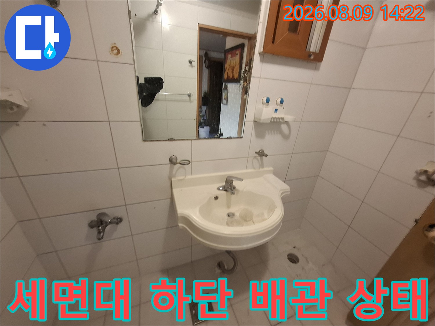 하얀색 세면대 아래쪽-타일 벽면과 수전 모습