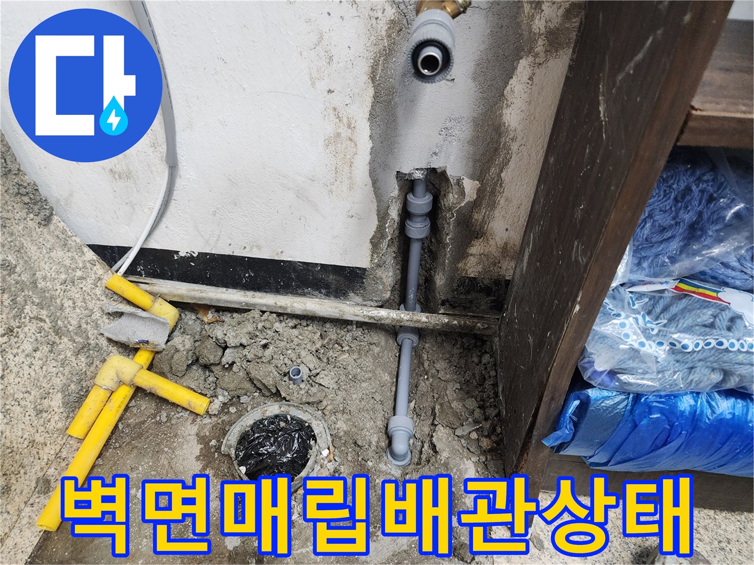 노출된 회색 배관과 누수로 인해 젖은 바닥 콘크리트 부위