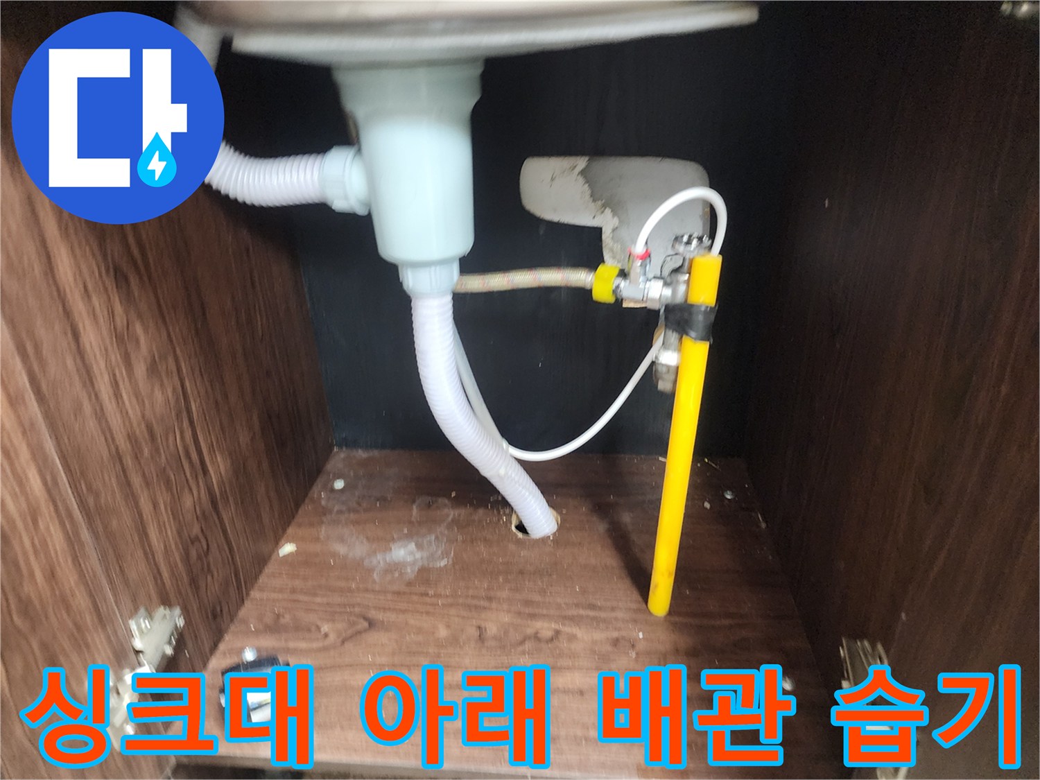 누수로 인해 젖어 있는 싱크대 하부장 바닥과 배수 호스 연결부