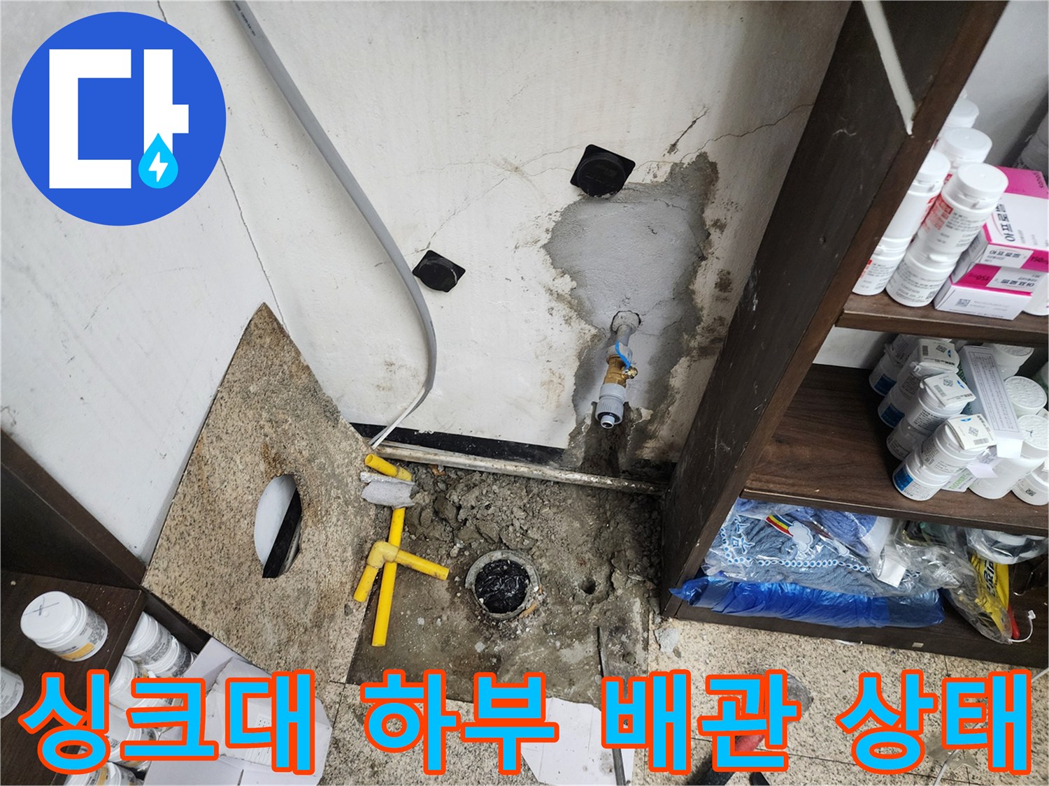 천안 동남구 싱크대 하부장 내부의 노후된 배관과 젖은 바닥 모습