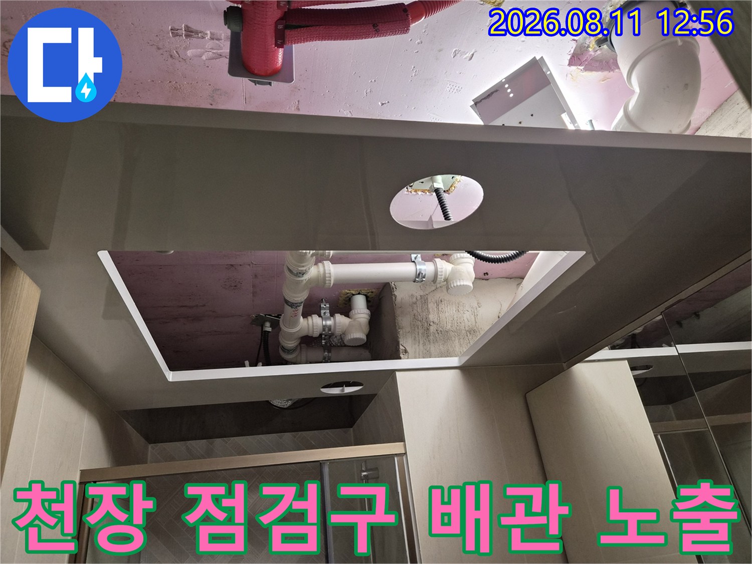 욕실 천장재 사이로 보이는 하얀색 배관과 분홍색 슬라브 표면