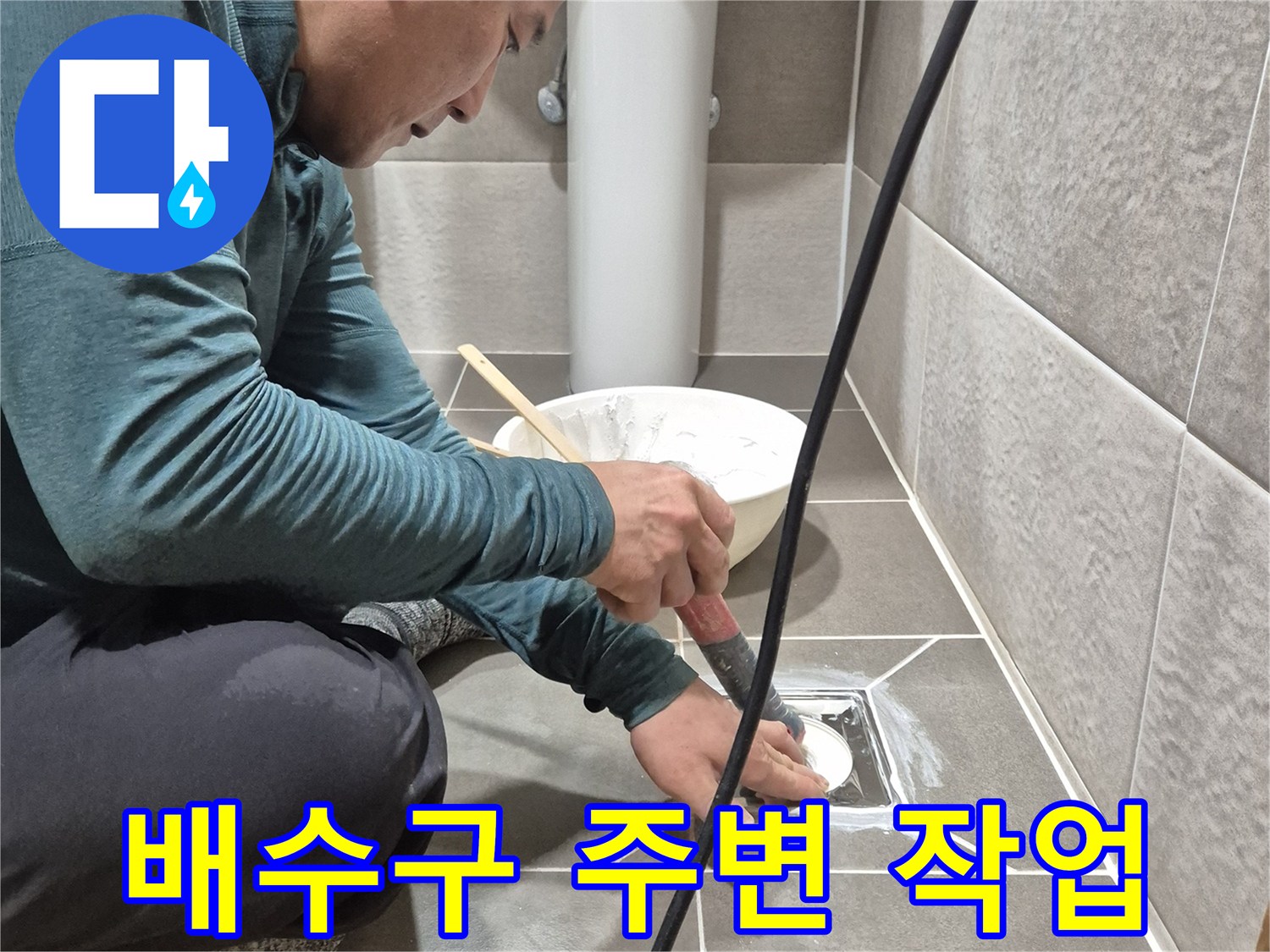 욕실 배수구 주변의 타일 틈새를 확인하며 작업하는 모습