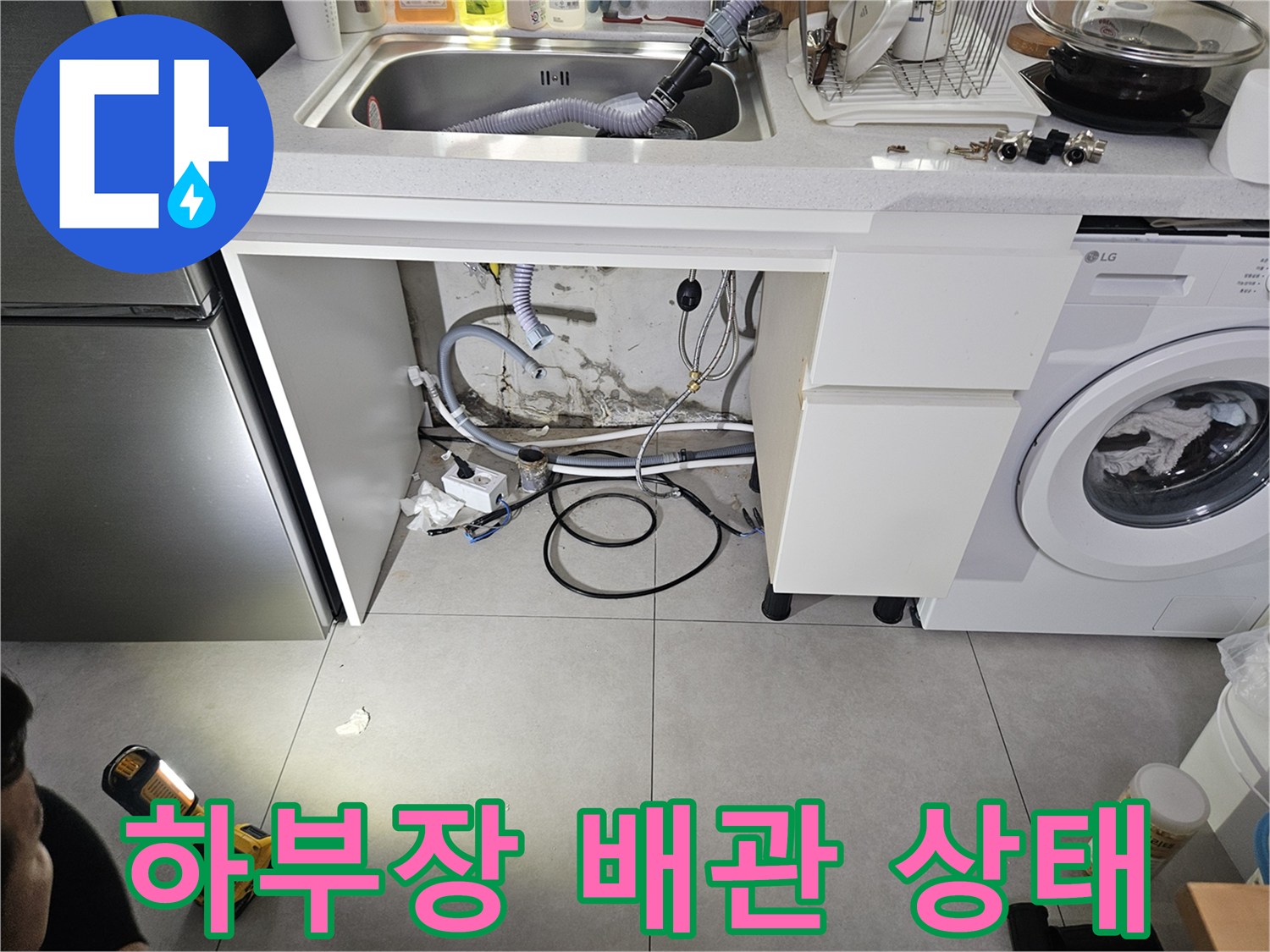 싱크대 하부장 안쪽 배관들의 연결 상태를 근접 촬영한 사진입니다.