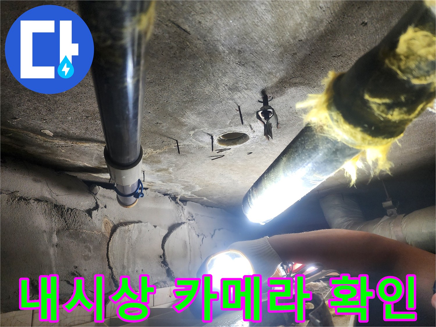 작업자가 밝은 빛으로-천장 내부 배관을 비추며 점검하는 모습