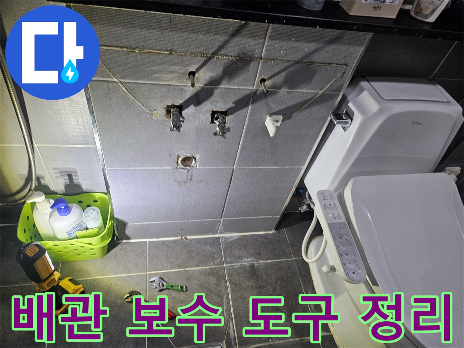 화장실 바닥에 놓여 있는 작업용 스패너와 전동공구 세트