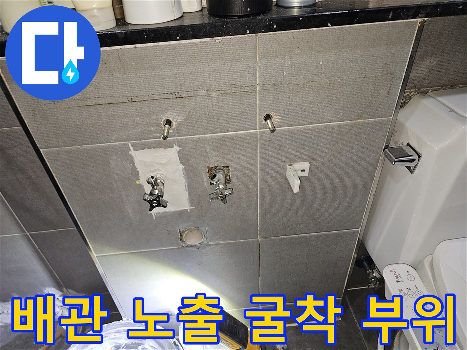 화장실 벽면 타일을 제거하여 내부 수도 배관을 드러낸 모습