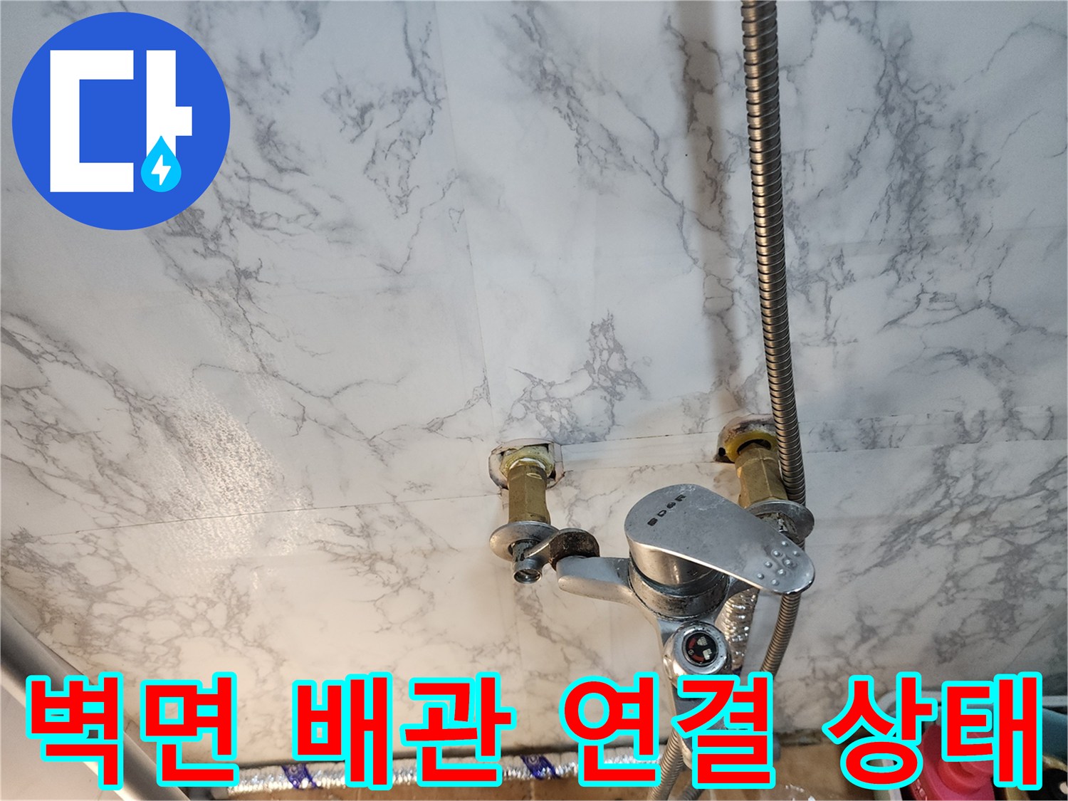 벽면에 설치된 수전 하단 금속 배관 및 호스 모습