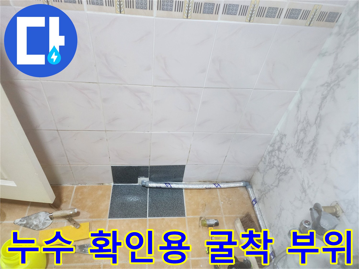 타일을 제거하여 드러난 배관과 주변의 작업 도구들