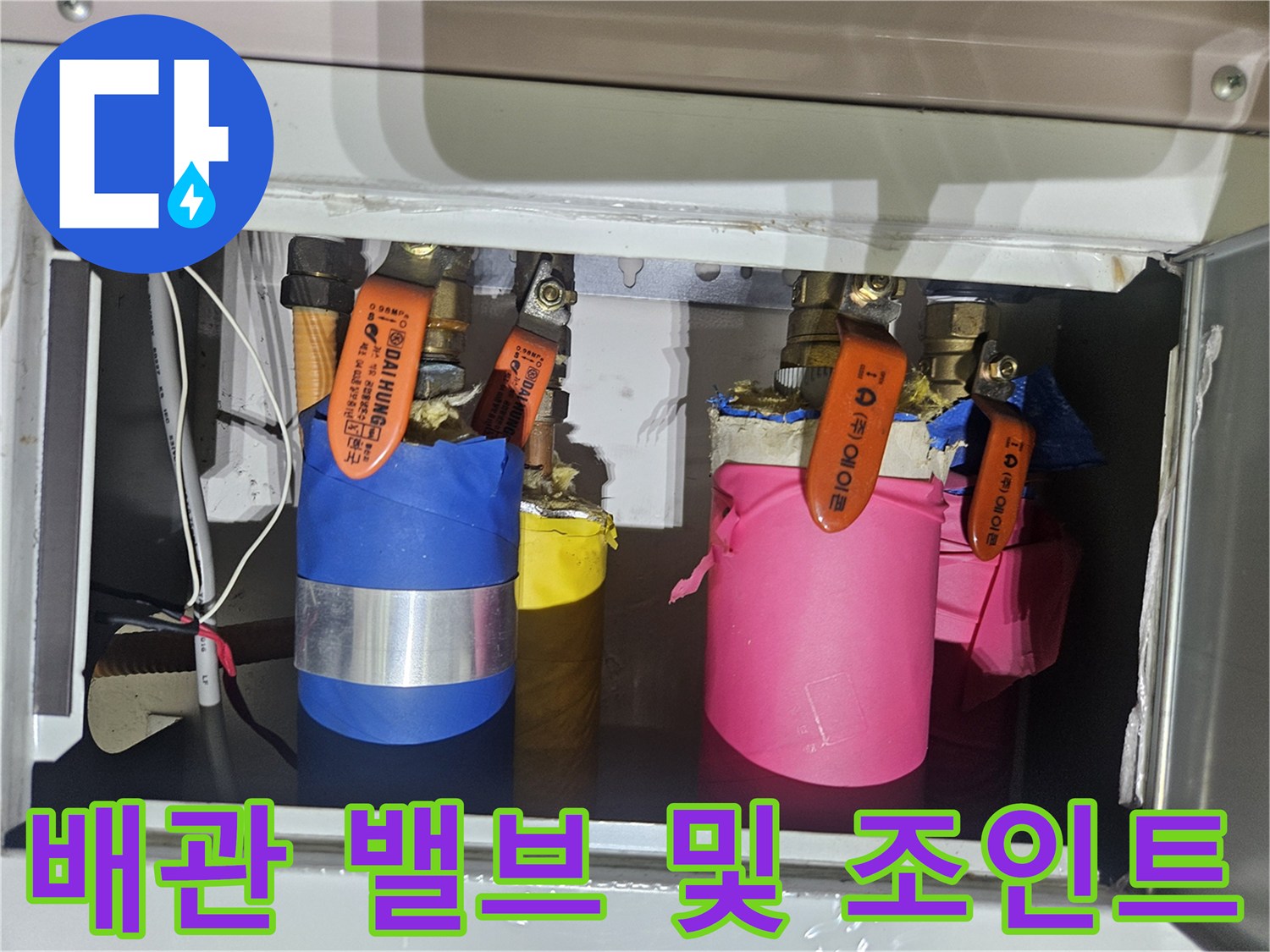 주황색 밸브가 달린 배관 연결 부위의 모습입니다.