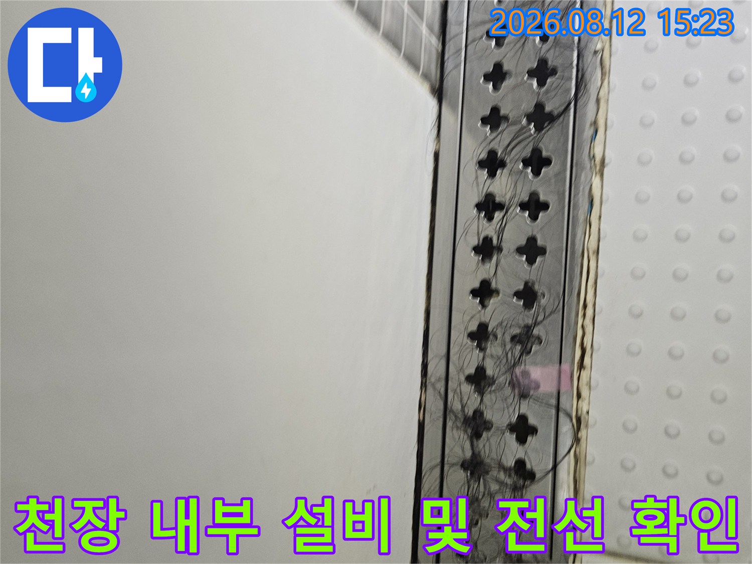 흰색 천장재 아래에 배치된 검은색 전선들과 격자 모양의 환기구 모습