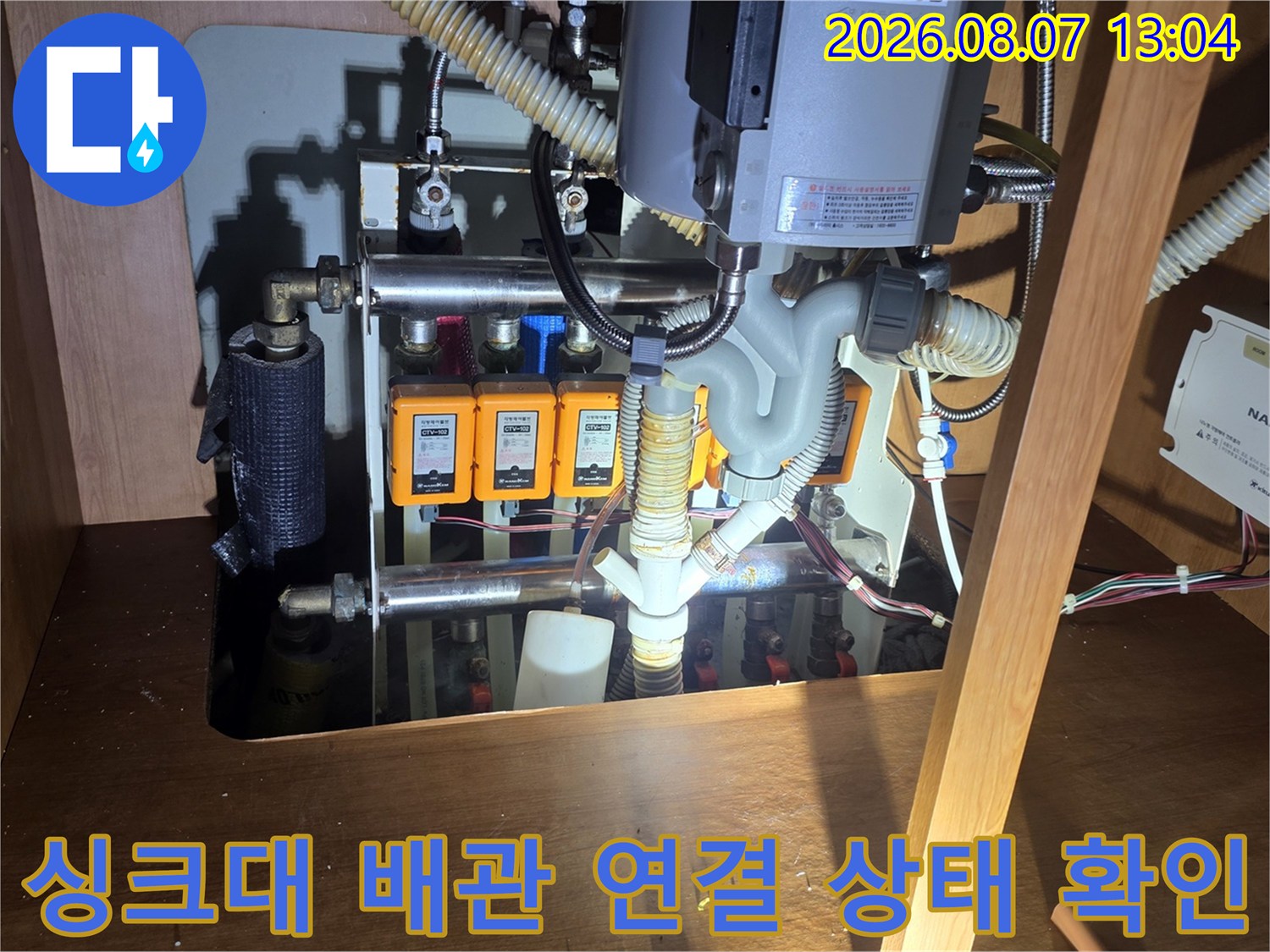 싱크대 아래쪽 앵글밸브와 배관의 연결 부위를 면밀히 관찰하고 있습니다.