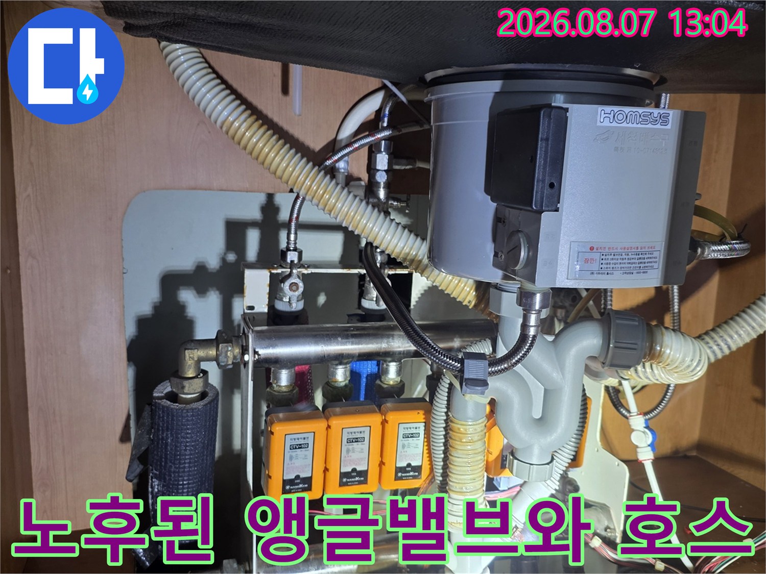 주방 싱크대 하부의 노란색 밸브 부품과 연결된 급수 호스 상세 사진입니다.