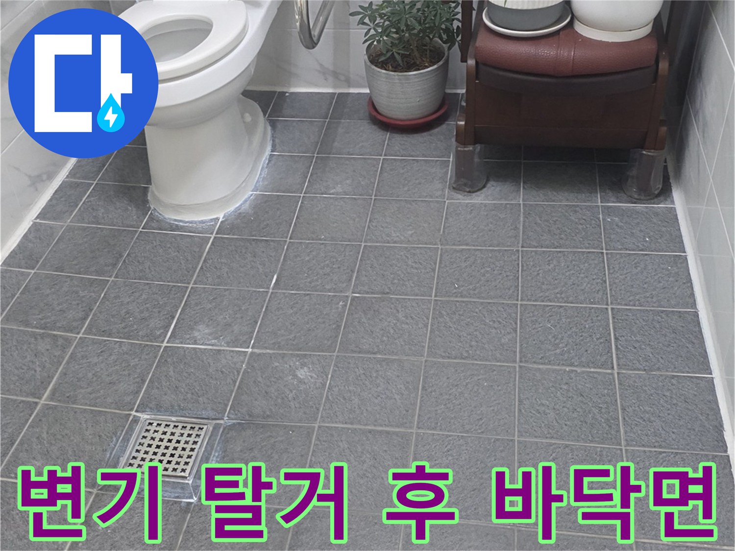 변기를 들어낸 자리의 화장실 타일과 배수구 모습