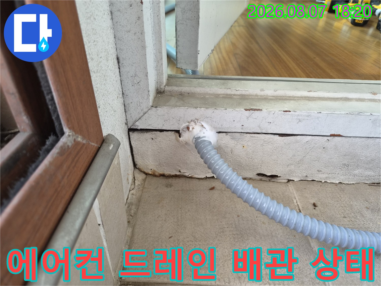 창틀 아래로 뻗어 나온 에어컨 배수 호스 구간