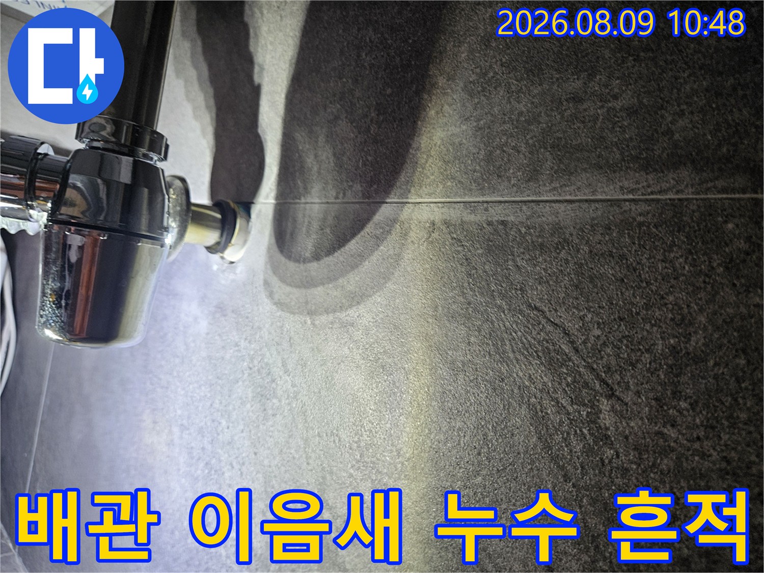 금속 배관 연결 부위 주변의 젖은 타일 표면 촬영