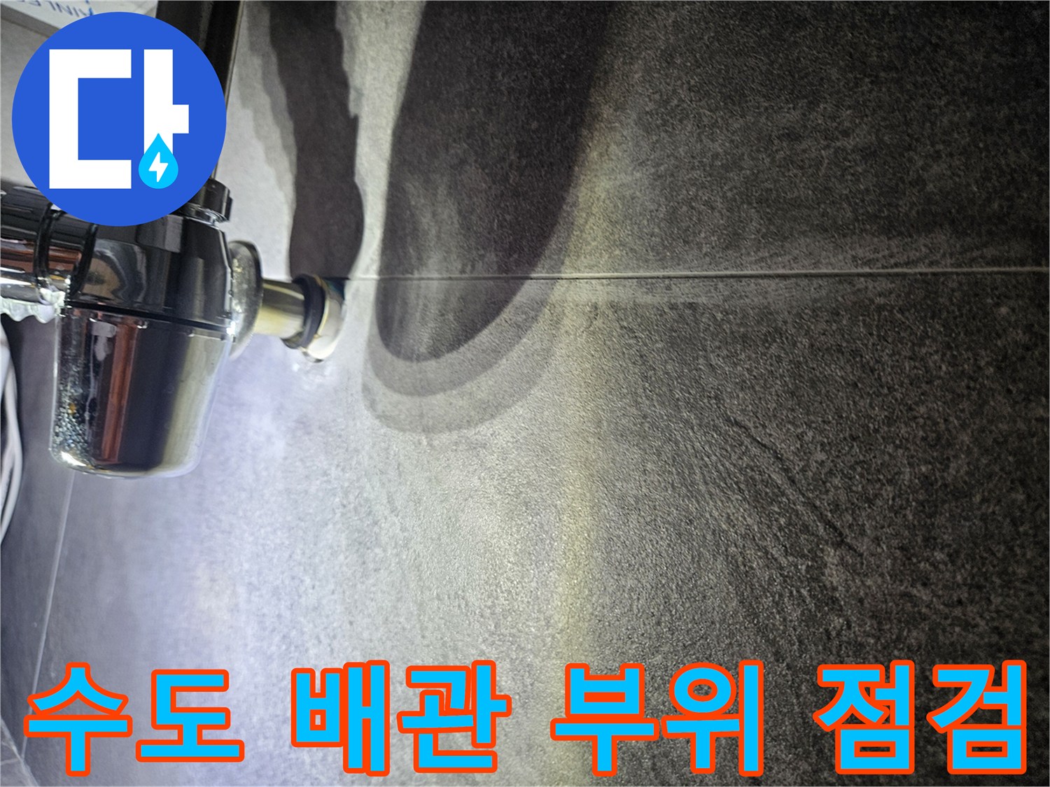 어두운 색 타일과 은색 배관의 접촉 지점