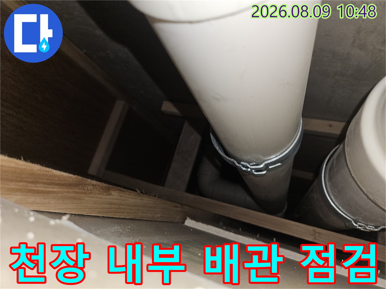 천장 목재 구조물 사이에 노출된 하얀색 하수 배관