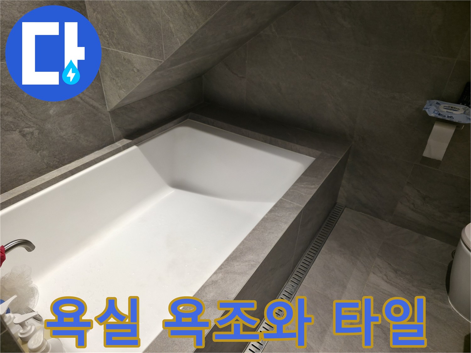 회색 타일로 마감된 욕실의 욕조와 배수구 모습