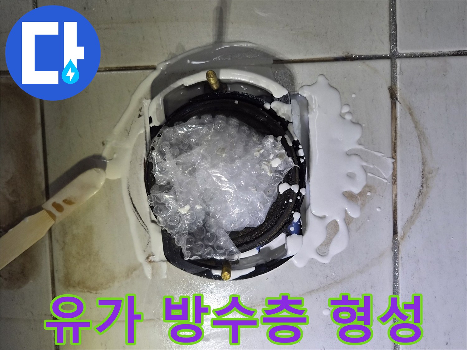 배수구 주변 틈새를 하얀색 방수제로 메우는 공사 현장 사진입니다.