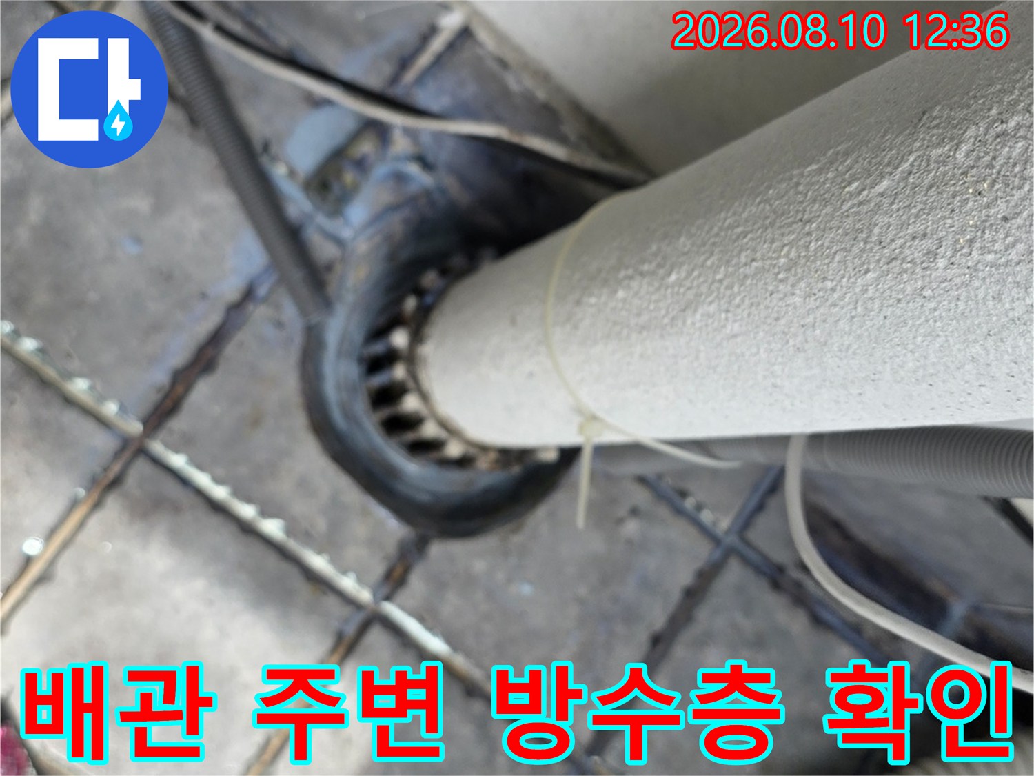 배관 하단부의 타일 틈새와 배관 접합 부위를 근접 촬영한 사진입니다.