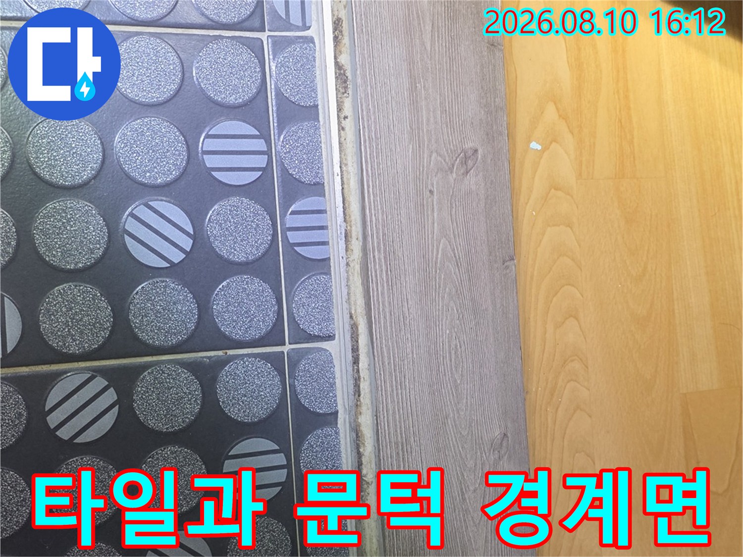 욕실 타일 패턴과 나무 문턱의 접합부 근접 촬영 사진