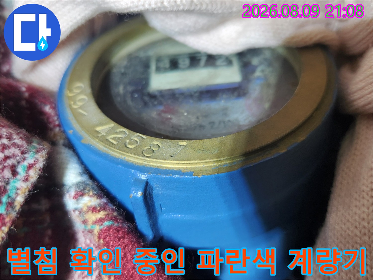 파란색 본체에 노란색 링이 둘러진 수도 계량기의 지표면 사진
