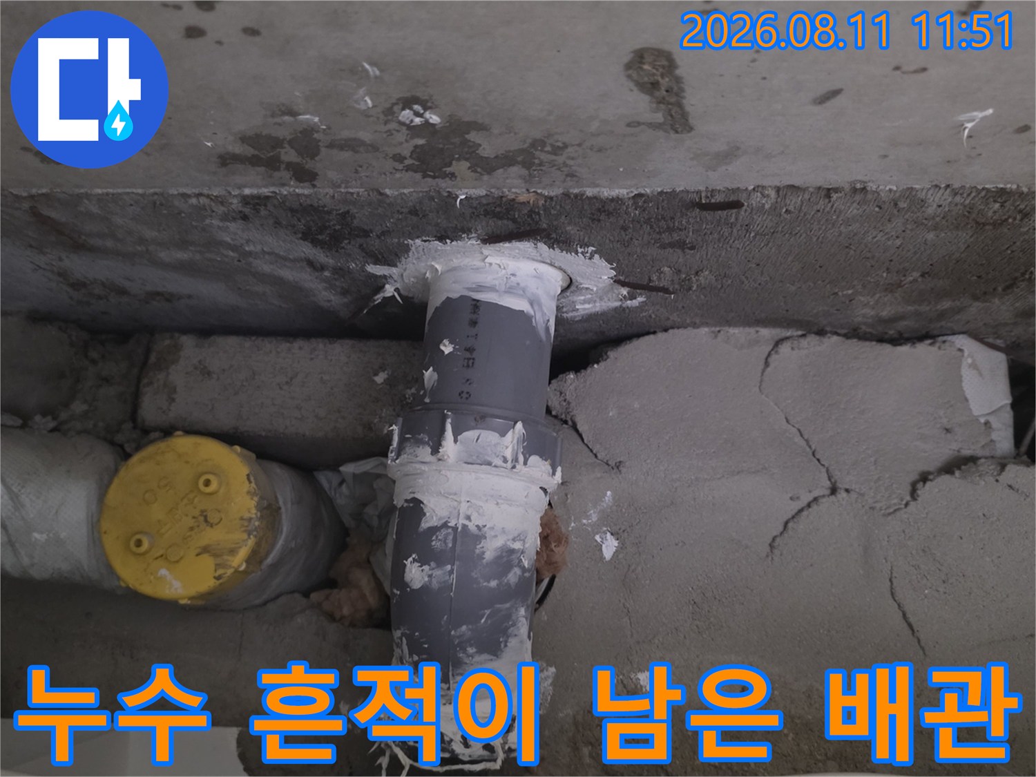 하얀색 마감재가 묻어있는-배관 연결 부위의 누수 흔적을 촬영한 사진입니다.