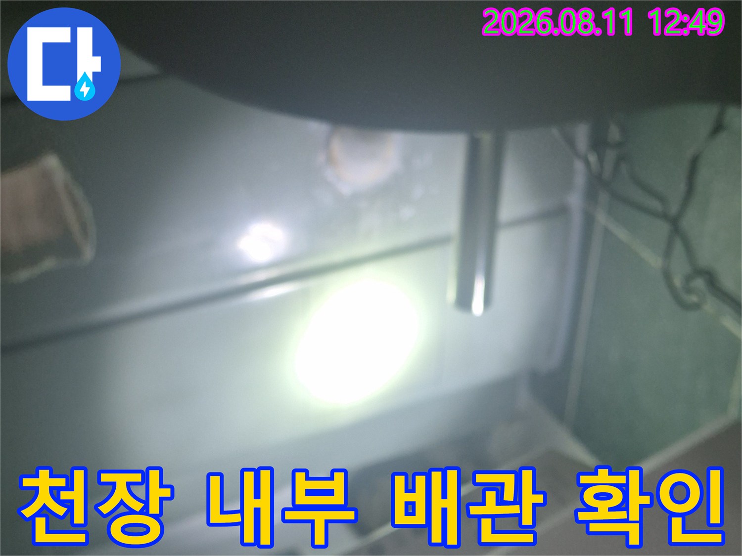 밝은 조명을 사용하여 천장 안쪽의 배관 연결 부위를 정밀하게 조사하고 있습니다.