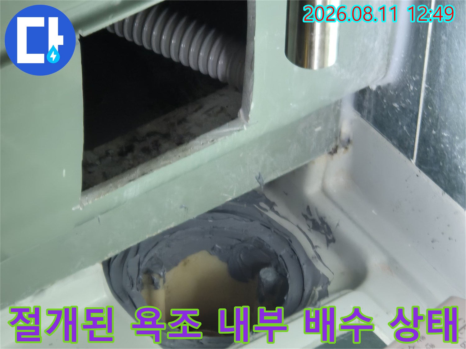 욕조 측면 틈새로 보이는 주름진 배수 호스와 연결 부위