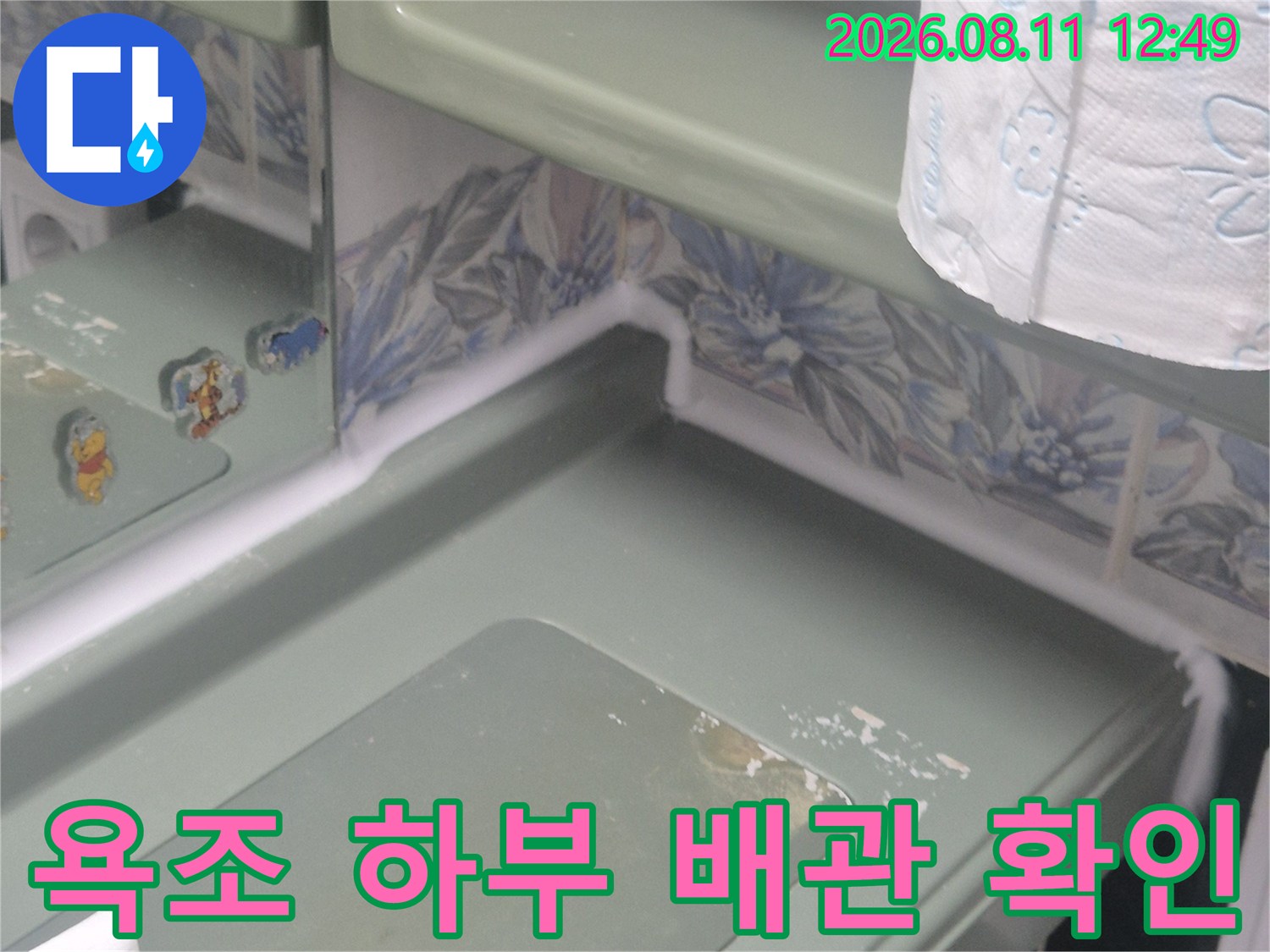 절개된 욕조 패널 사이로 드러난 내부 구조와 배관 주변 상태입니다.