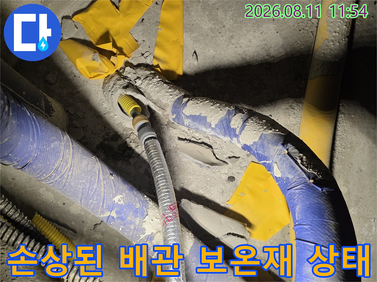 파란색 보온재가 찢겨져 있는 노출 배관의 근접 사진입니다.