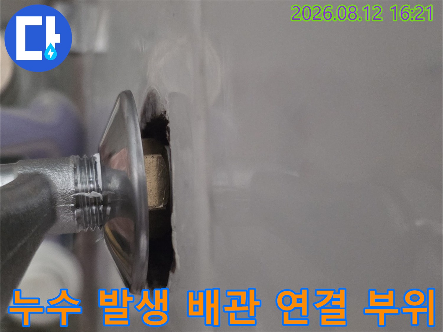천장 마감재에 뚫린 구멍을 통해 보이는 금속제 나사산 배관 연결부