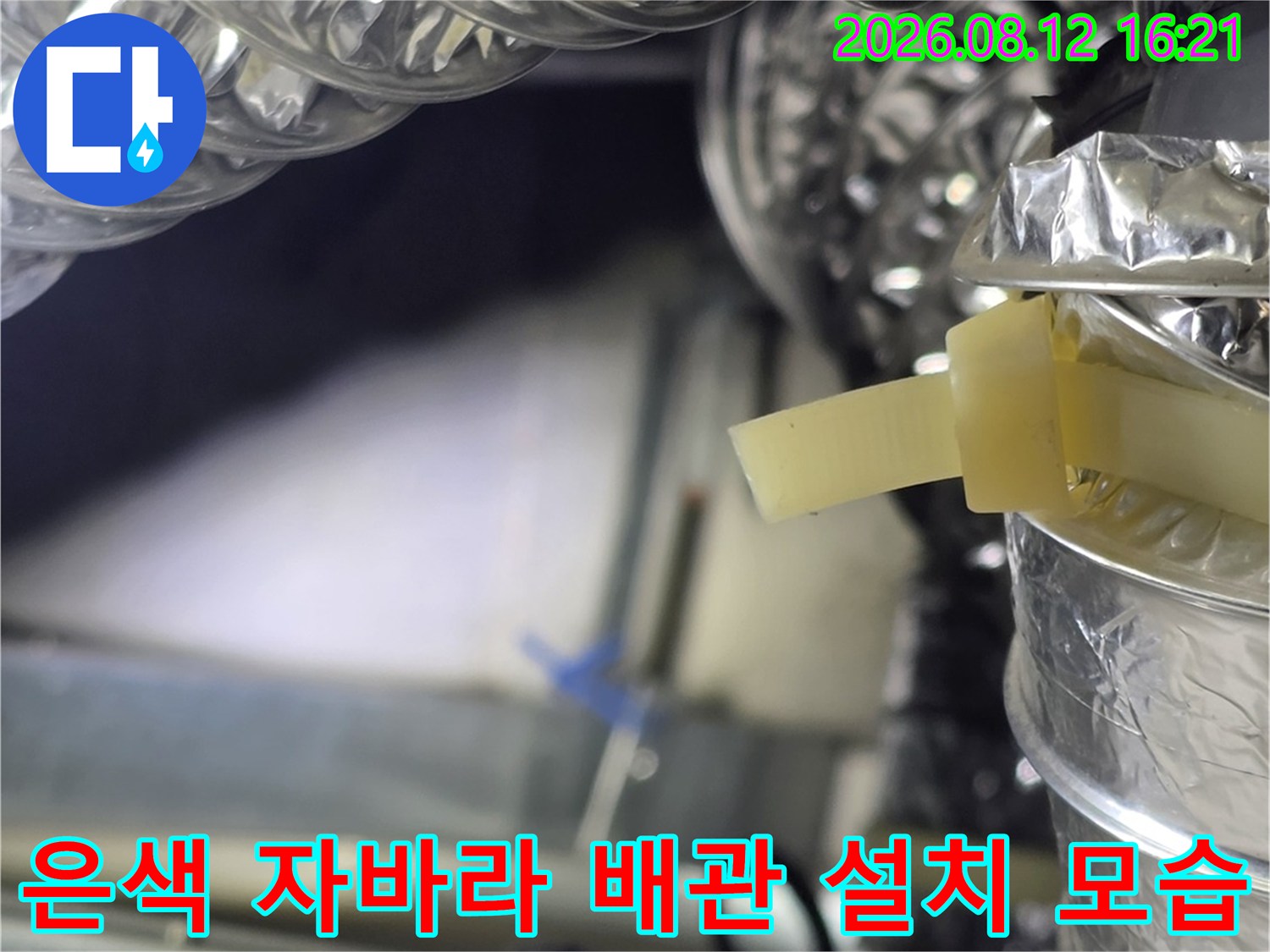 천장 속 공간에 설치된 은색의 주름진 배관과 고정 테이프의 모습