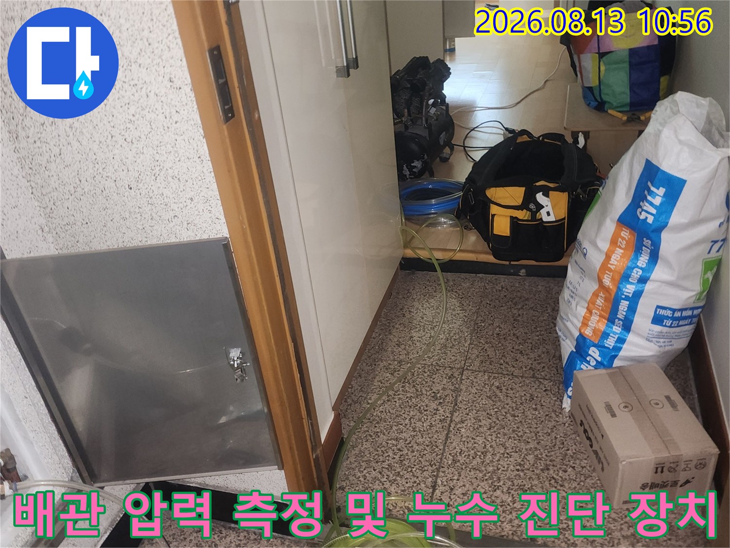 화장실 바닥의 스테인리스 점검구와 연결된 공압 테스트용 호스-사진