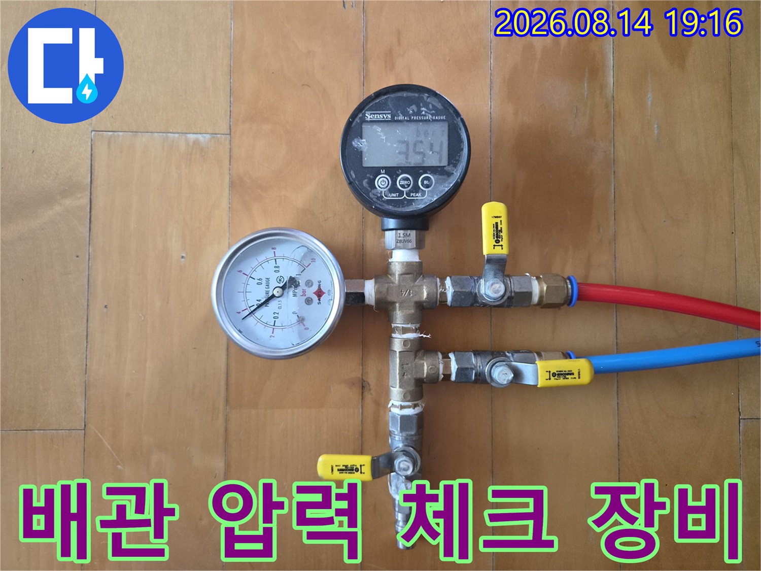 빨간색과 파란색 호스가 연결된 배관 점검용 밸브와 게이지입니다.