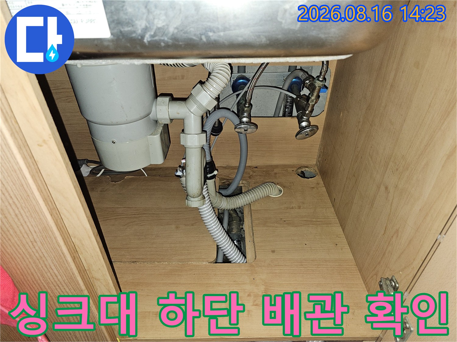 싱크대 아래쪽의 복잡한 배관 연결 구조와 호스들