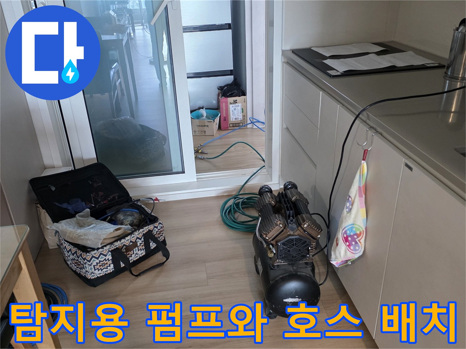 바닥에 놓인 검정색 압력 테스트 장비와 파란색 배관 호스