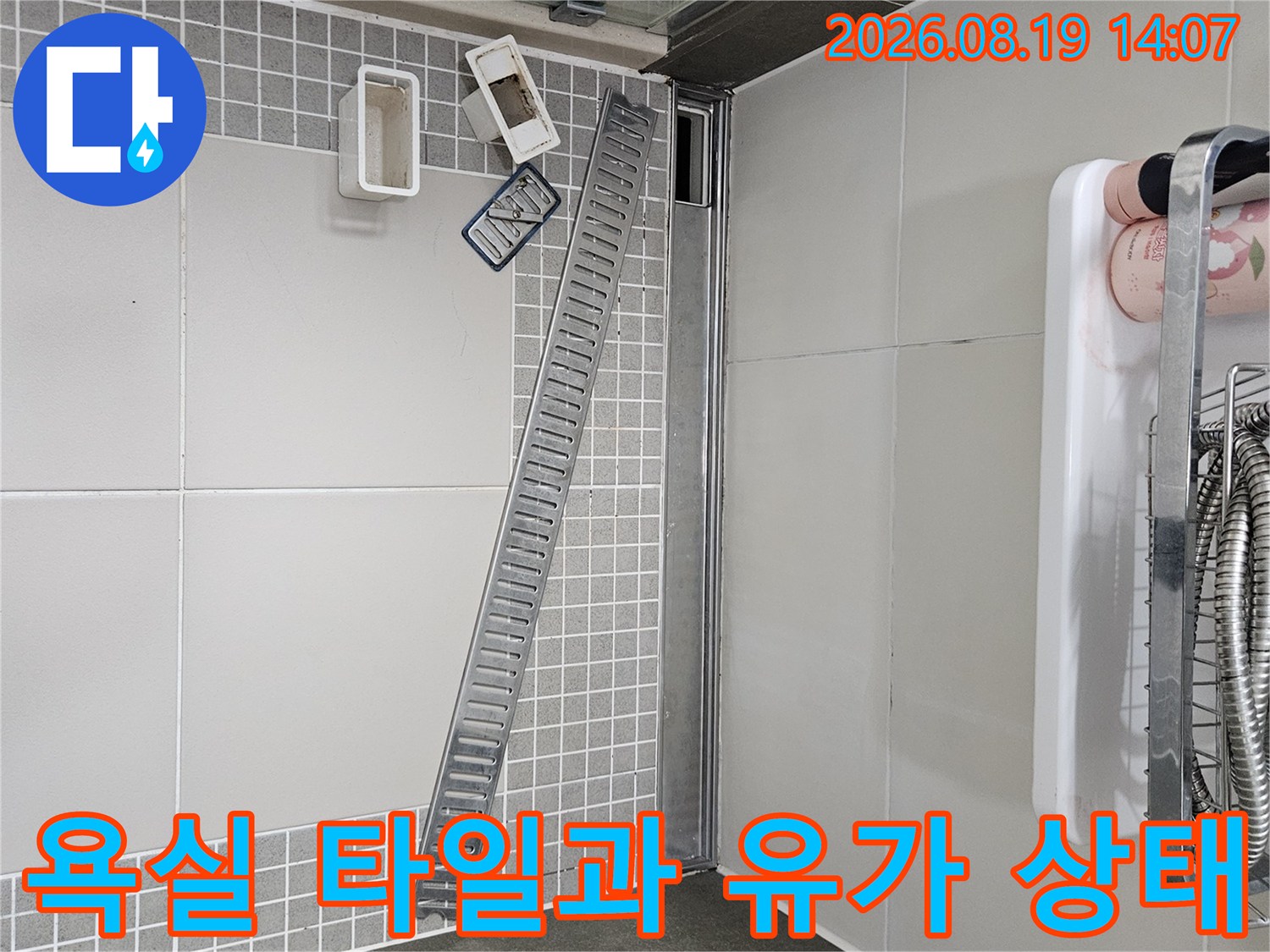 밝은색 대형 타일과 긴 스테인리스 배수구의 결합 부위