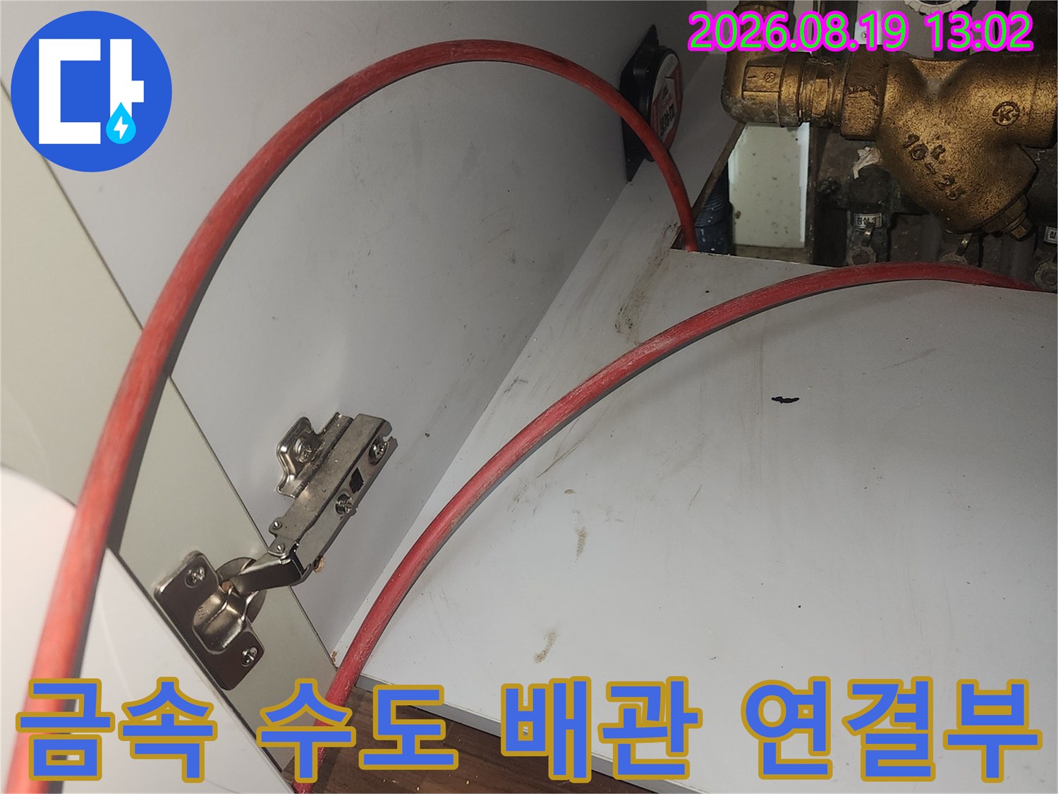 주방 싱크대 하부의 황동색 금속 밸브와 호스 연결 상태