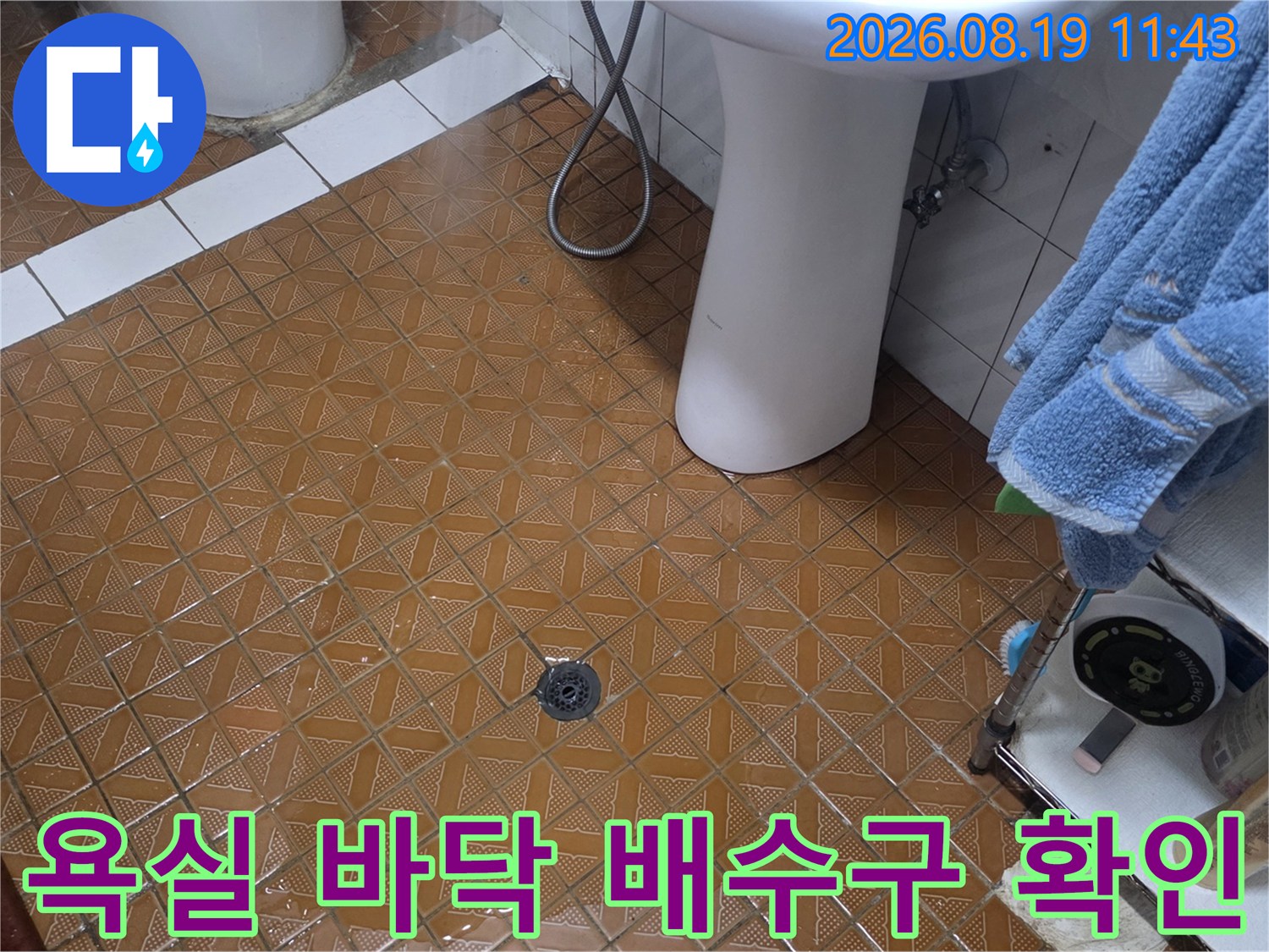 갈색 사각형 타일과 세면대 아래 배수구 부위 촬영