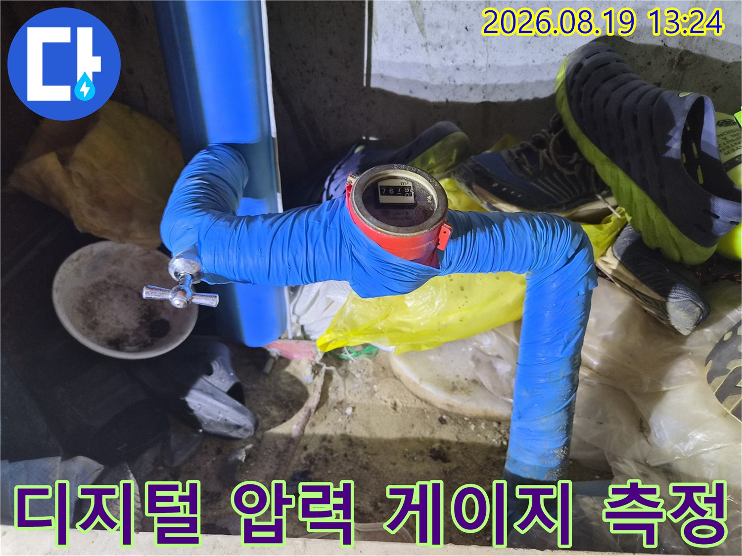보온재로 감싸진 파란색 배관과 디지털 수압계의 연결 부위