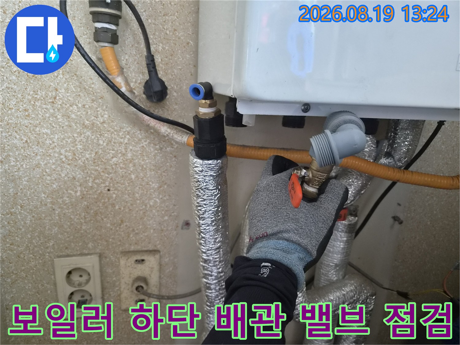 은색 보온재로 마감된 배관과 밸브 조절 장치를 근접 촬영하였습니다.