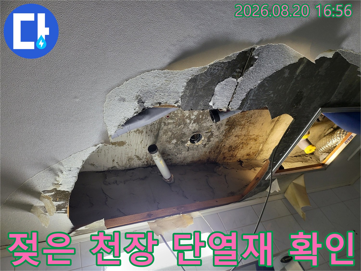 물에 젖어 변색된 천장 내부의 유리섬유 단열재와 배관 모습입니다.